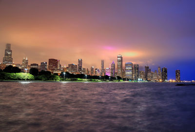 Illuminated buildings in city against sky