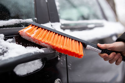 Winter problems with the car. a man cleans the car from snow with a brush