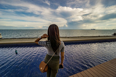 Rear view of woman on beach against sky