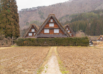 Road amidst trees and houses against mountain