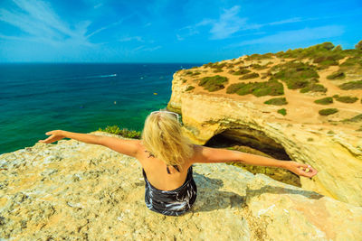 Woman sitting on rock against sea