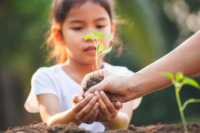 Close-up of girl holding plant in hand with mother outdoors