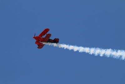 Low angle view of airplane flying against clear blue sky