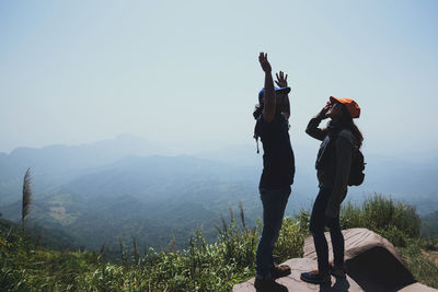 People standing on mountain against sky