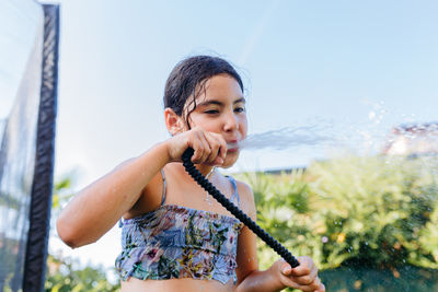Low angle view of child drinking directly from hosepipe on a sunny hot day