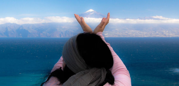 Close-up of woman hand in sea against mountains