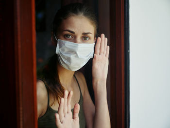 Portrait of young woman standing by window