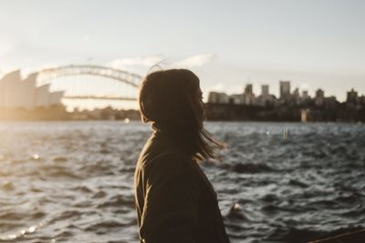 Side view of woman standing by river in city