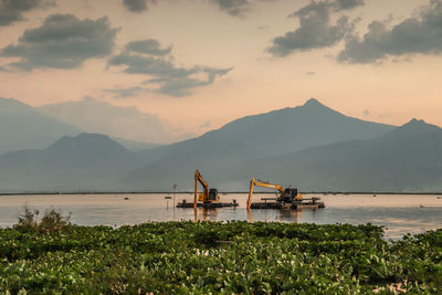 Built structure by lake against sky during sunset