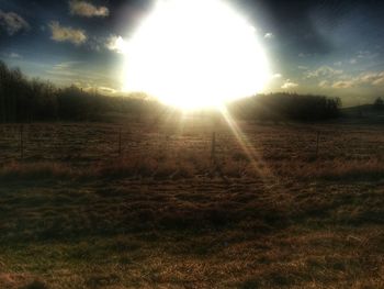 Scenic view of grassy field against sky at sunset