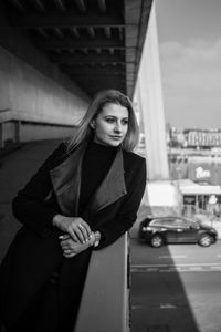 Portrait of beautiful woman in city against sky