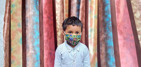 Close-up portrait of boy against curtain