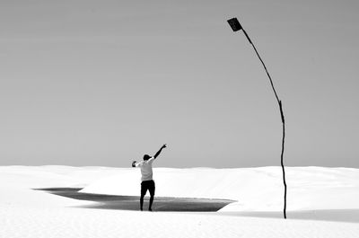 Rear view of man flying kite against clear sky