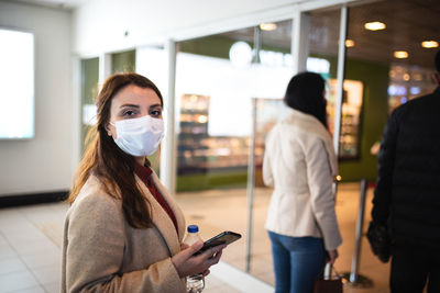 Young woman wearing mask standing at mall