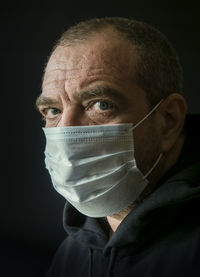 Portrait of man wearing mask against black background