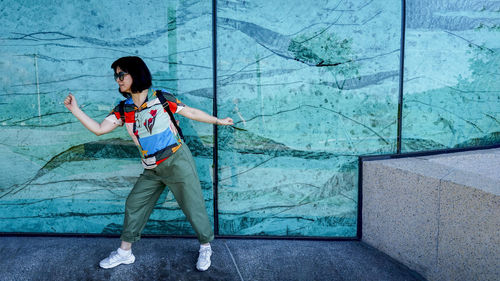 Full length of girl standing against wall