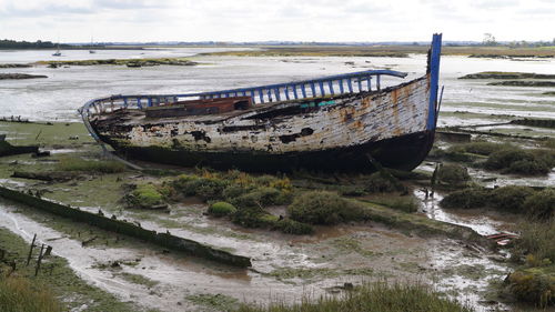 Abandoned wooden dingy boat on the mud flats beach maritime background image 