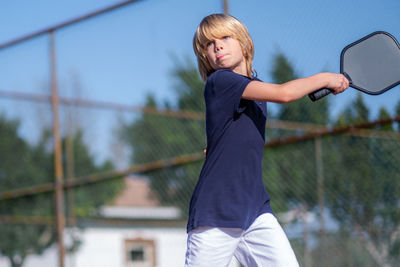 Side view of young man playing tennis