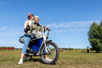 Woman riding motorcycle on field against sky