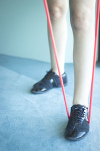 Low section of woman exercising with red resistance band on floor