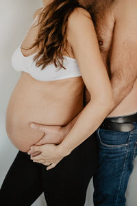 Midsection of couple standing against gray background