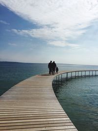 Rear view of people amidst sea on pier