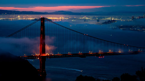 View of suspension bridge in city at dusk