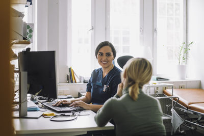 Smiling female nurse listening to female patient during visit in clinic