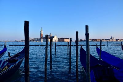 Wooden posts in canal against clear blue sky