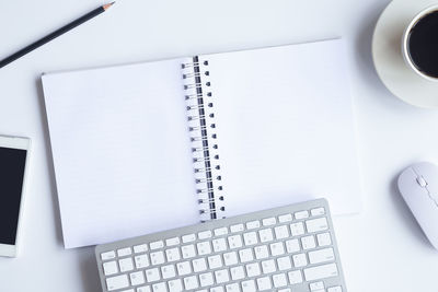 Directly above shot of note pad with coffee and office supplies on table