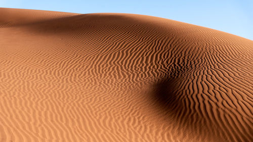 Sand dunes in desert against clear sky