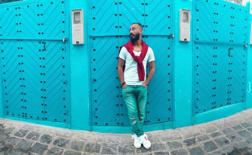 Portrait of happy man leaning against blue wall