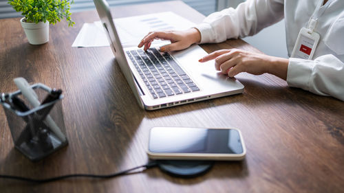 Midsection of woman using digital tablet on table