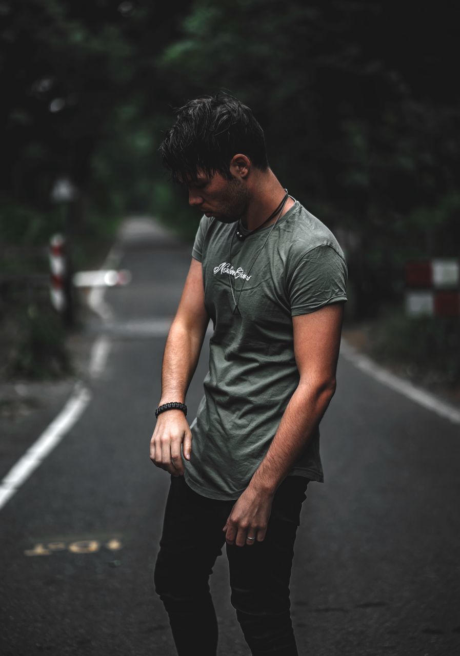 three quarter length, one person, casual clothing, road, real people, focus on foreground, standing, leisure activity, young men, young adult, lifestyles, transportation, men, city, street, day, outdoors, looking, nature