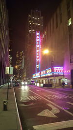 Illuminated city street against sky at night