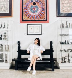 Full length portrait of young woman sitting at home