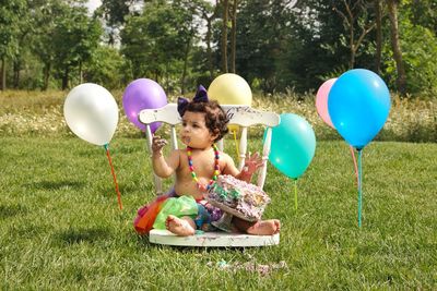 Girl holding balloons on grassland