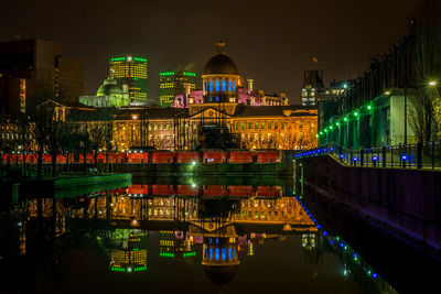 Illuminated bonsecours market reflection in sea against sky at night
