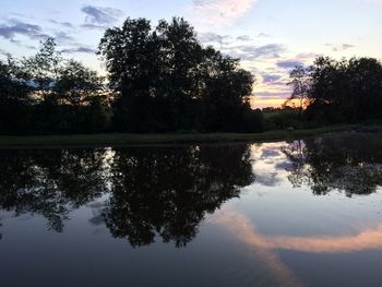 Reflection of silhouette trees in lake against sky