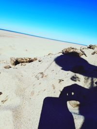 Shadow of person on beach against clear blue sky