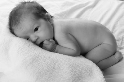 Close-up portrait of baby girl lying on bed