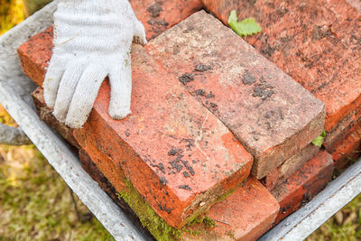 High angle view of worker hand picking brick from wheelbarrow at construction site