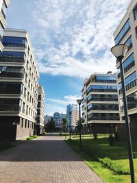 Footpath amidst buildings in city against sky