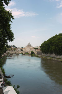 View of buildings by river against cloudy sky