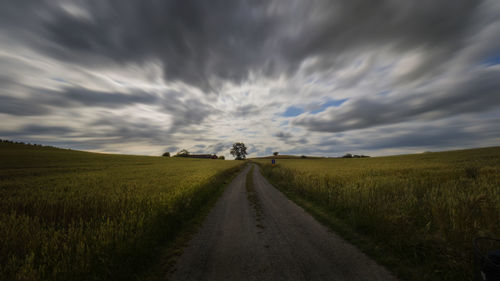 Road amidst field against sky