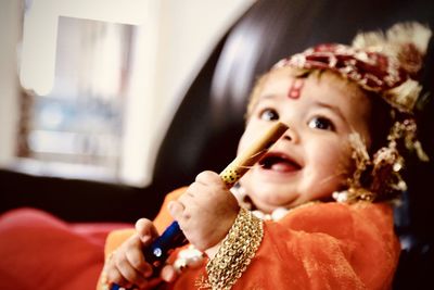 Close-up of cheerful baby boy wearing traditional clothing while sitting on sofa