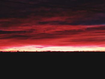 Silhouette landscape against dramatic sky during sunset