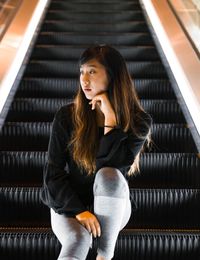 Woman sitting on escalator