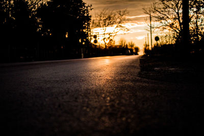 Road amidst trees against sky at sunset