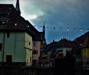 Rear view of couple against sky in city